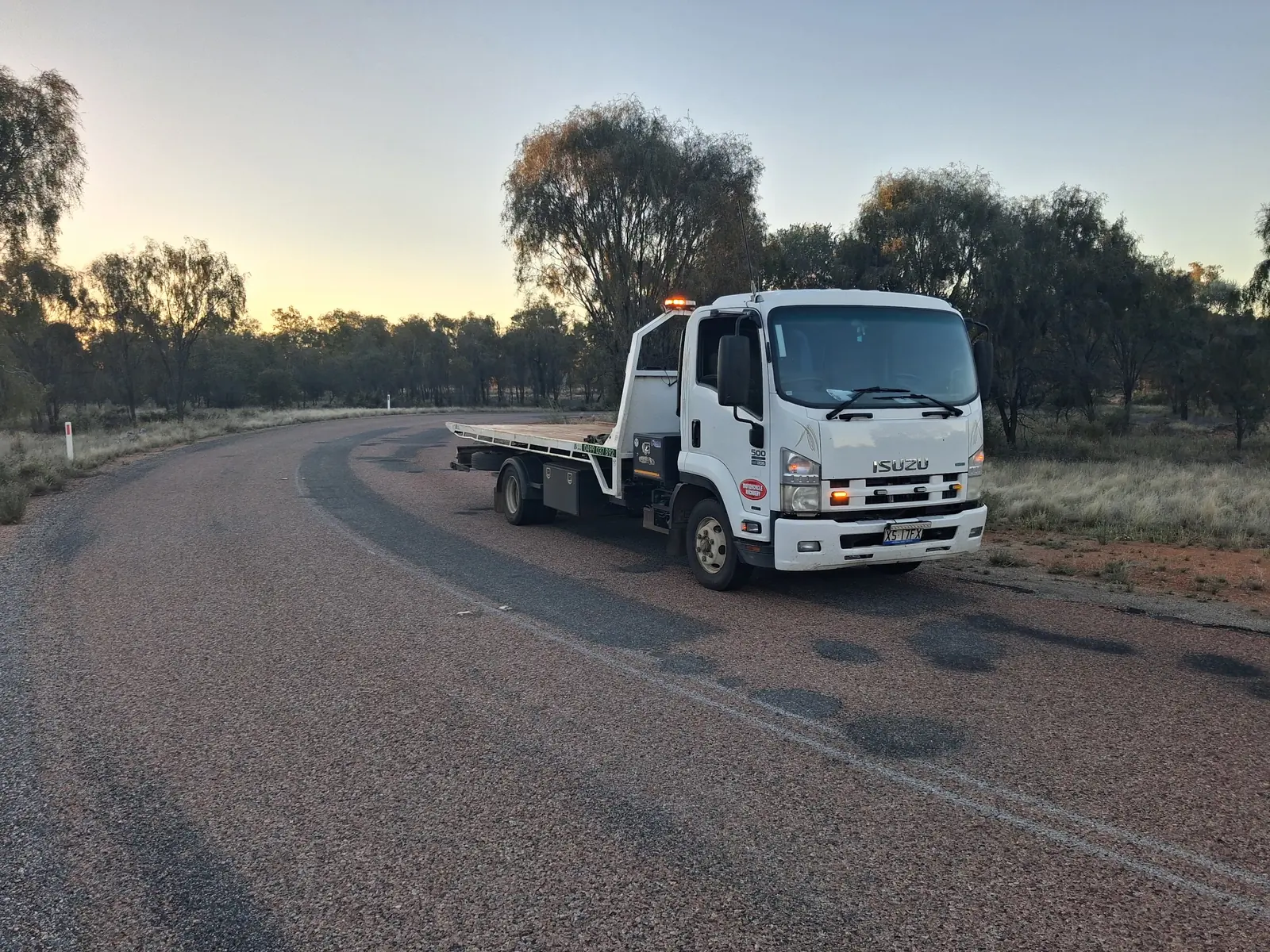 A.R Towing's tilt tray parked on a curving outback road at dusk