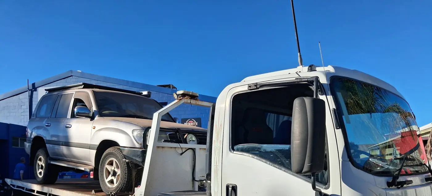 A silver LandCruiser on the back of A.R Towing's white Isuzu